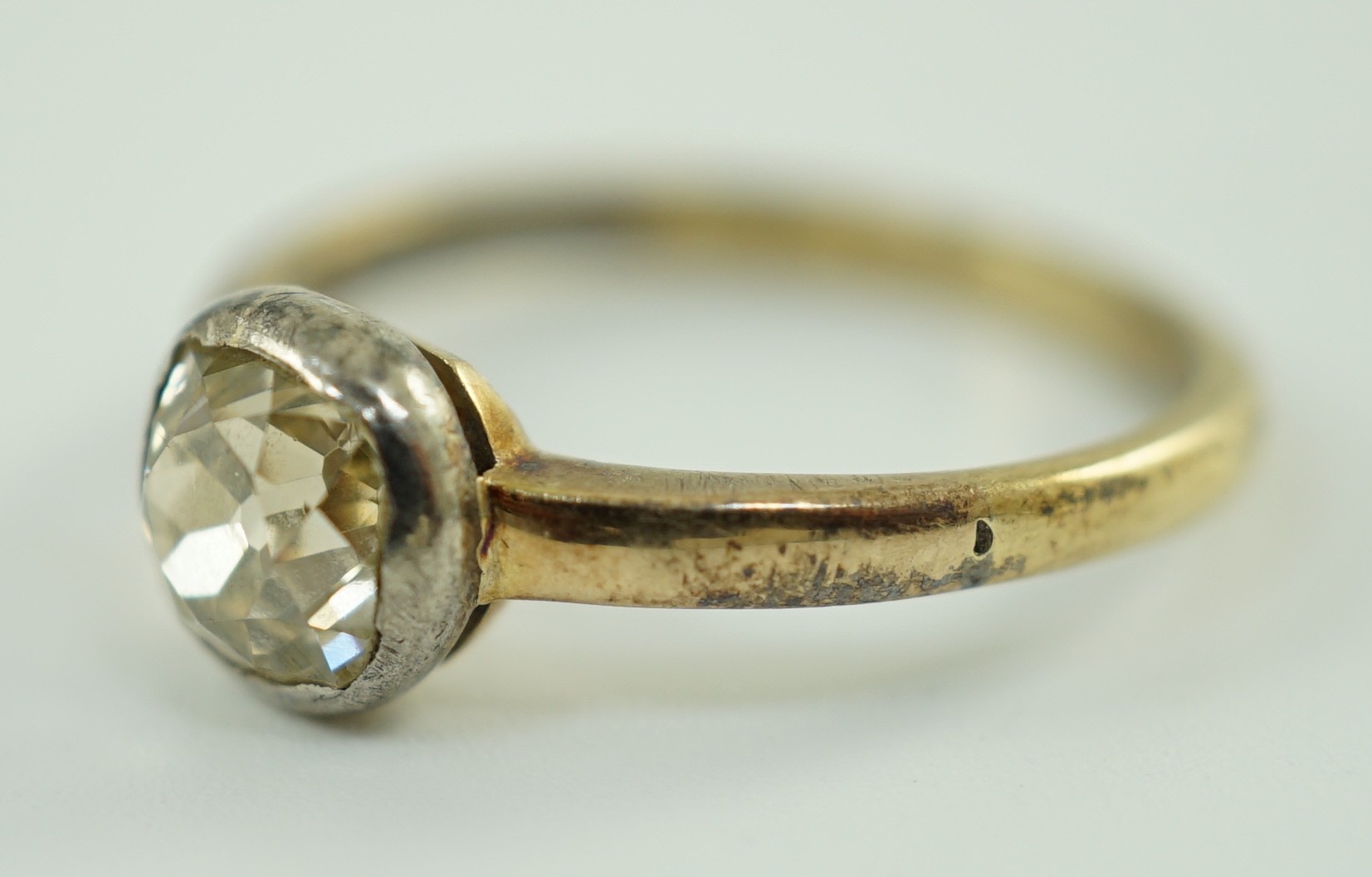 An antique yellow metal and collet set solitaire old cushion cut diamond ring